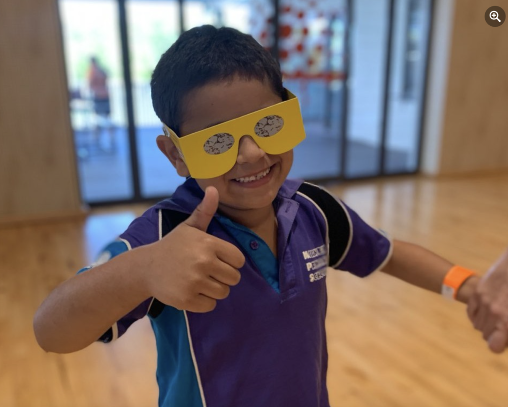 Young student wearing simulation glasses smiling at the camera giving a thumbs up